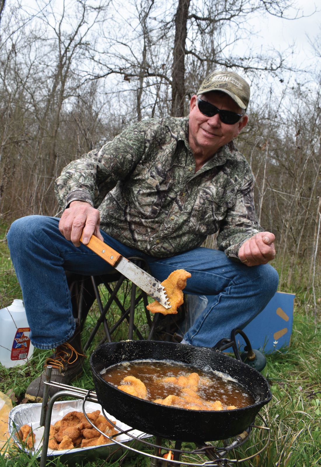 A young Larry Weishuhn checks to see what's cooking in the camp's Dutch oven